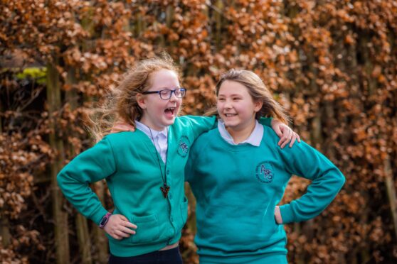 Pupils Maya Tyrrell and Ellie Sutherland laughing heartily with their arms around one another