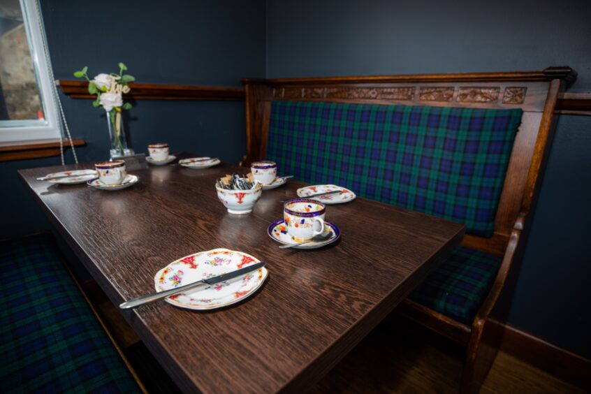 Table with old fashioned China settings and tartan upholstered bench