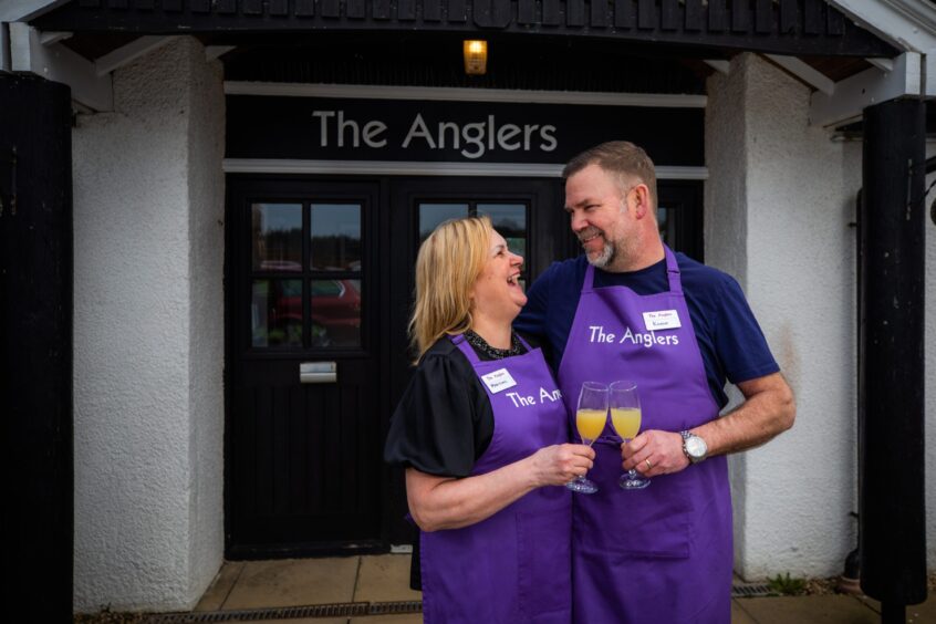 Martine and Kev Sinclair standing at back door to the Anglers at Guildtown, the couple are smiling with their arms around each other