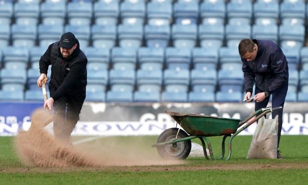 Ground staff work on the Dens Park pitch. Image: SNS