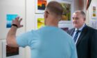 Perth prison governor Andy Hodge talking to one of the artists in front of a wall of paintings