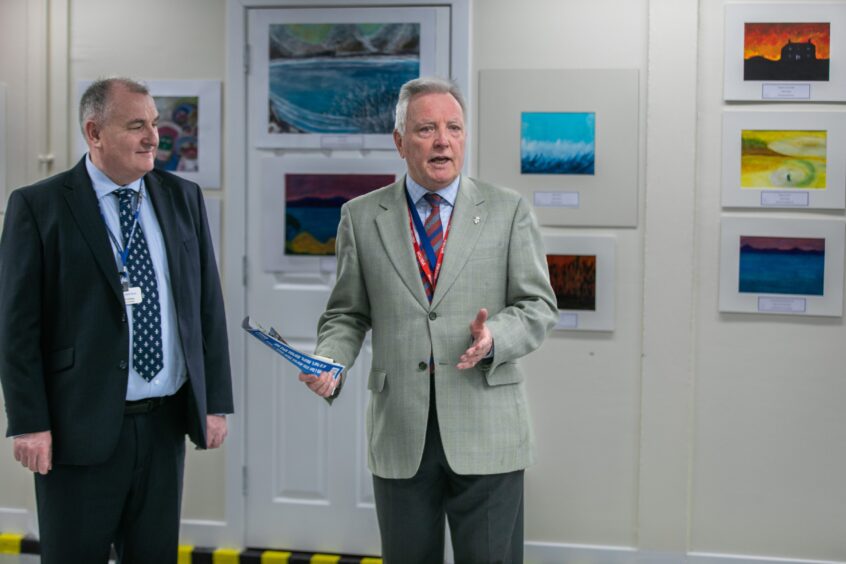 Andy Hodge and Andy Middlemiss standing in front of a wall of paintings at Perth Prison