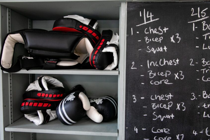 Boxing gloves and a board with exercise plans on it at Murray McDowell's Routine Health and Fitness gym in Perth.