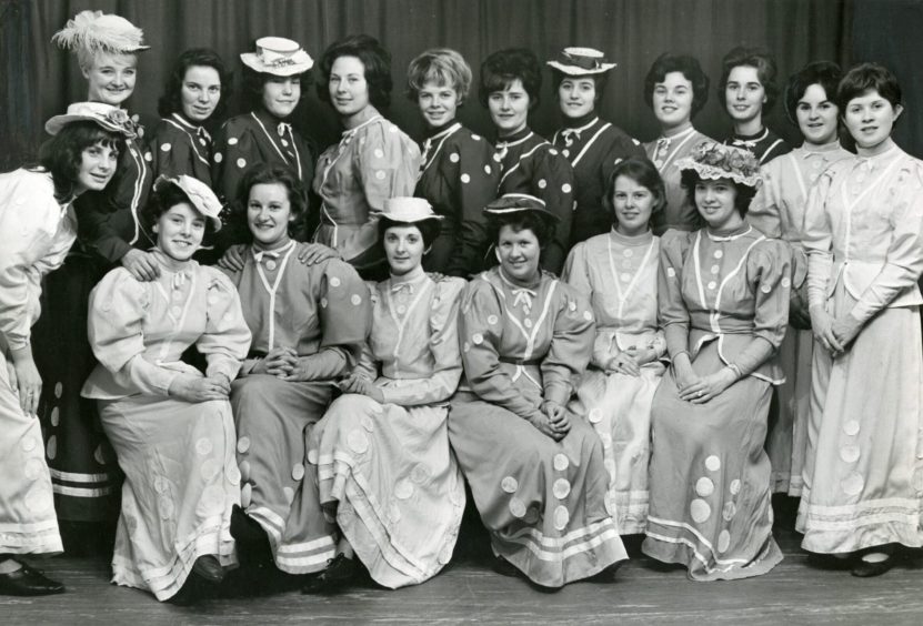 Ladies of the thomson-leng musical society in dresses on stage