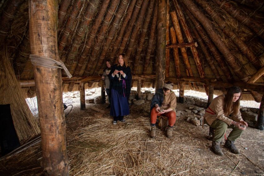 Some of the Crannog team members in costume working on crafts (drop spinning and making pots).
