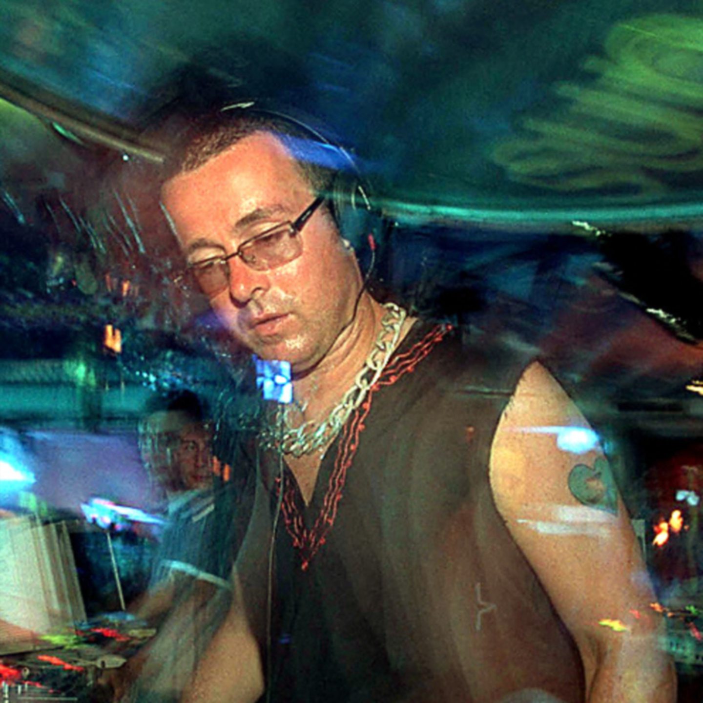 DJ Judge Jules wearing glasses and headphones at his mixing desk