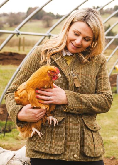 Sarah Rankin stands with a chicken in her arms. 