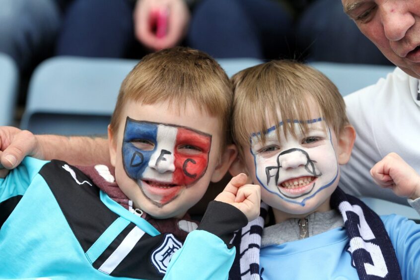 Young Dundee FC fans with their faces painted smile for the camera