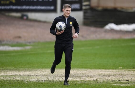 Referee David Dickinson inspects the Dens Park pitch. Image: SNS
