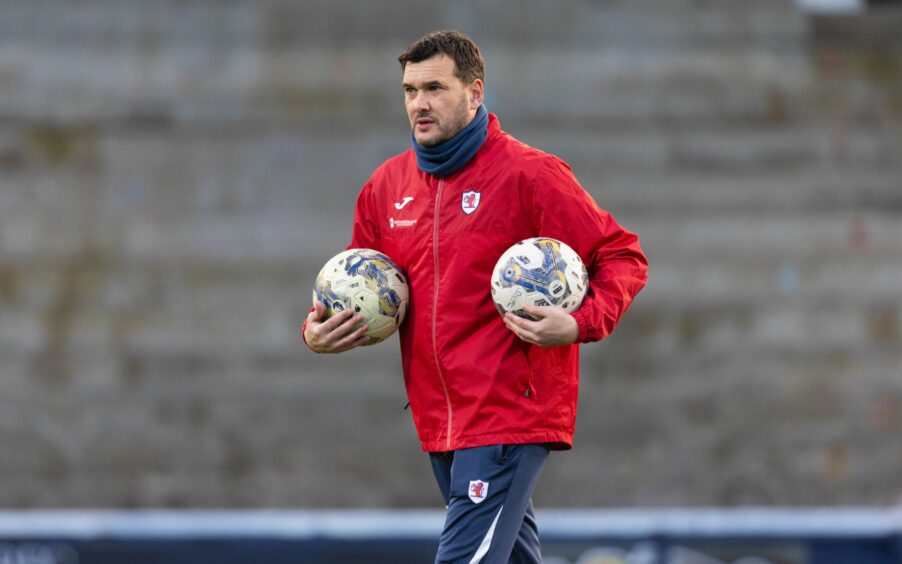Raith Rovers manager carries footballs under both arms.