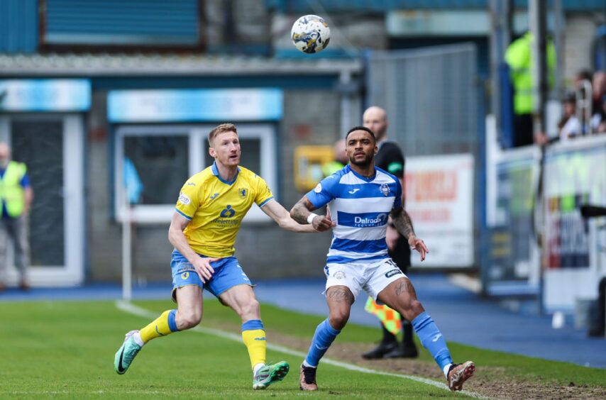 Raith Rovers defender Liam Dick and Morton's Jai Quitongo both have their eyes on the ball above their heads.