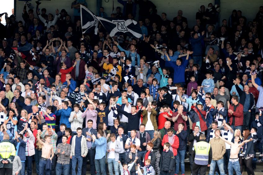 The Dundee fans singing and waving their arms in one of the Dens Park stands