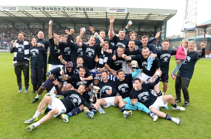 The Dundee players and staff celebrate on the pitch with the trophy after winning the league in 2014. 