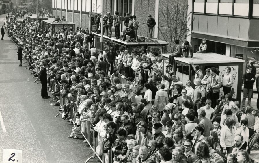 A crowd of spectators outside the Overgate Centre in 1984, with some perched on bus stops