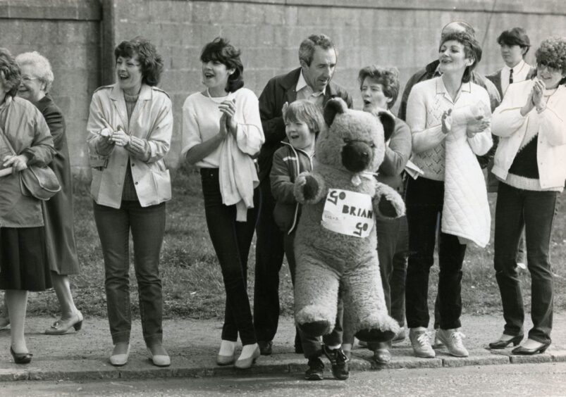Runners are cheered by spectators at the Stannergate, with one young onlooker holding a giant teddy bear