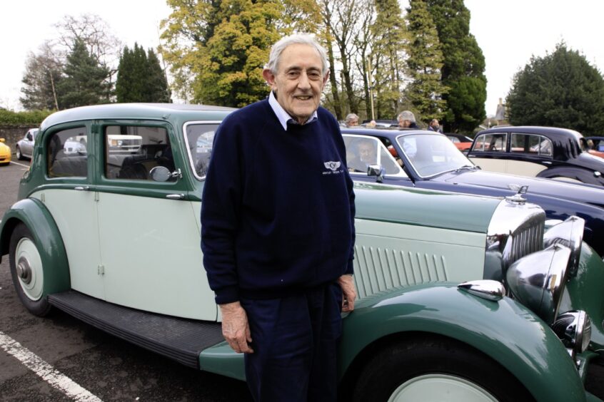 Older man standing next to green 1936 Bentley Derby car