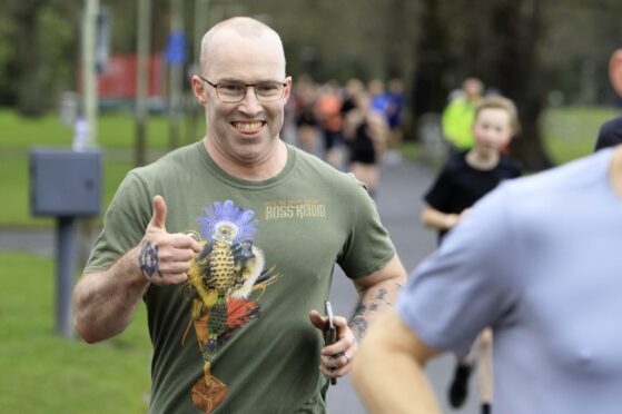 Steven McCready giving thumbs up gesture as he goes round parkrun course at Perth's North Inch with other runners
