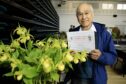 Cyril Lafong holding certificate in front of yellow flowers