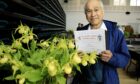 Cyril Lafong holding certificate in front of yellow flowers