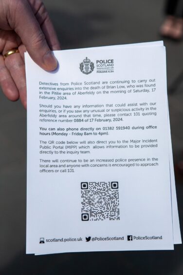 Hand holding a police leaflet urging people to come forward with information
