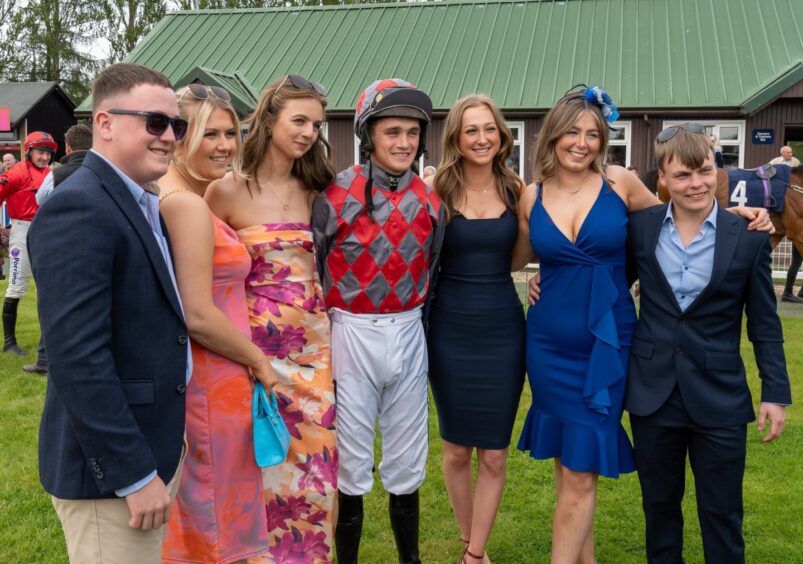 guests pose for a photo with a jockey as they attend ladies day at Perth Races