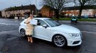 woman stands in front of a white car she won in an online raffle