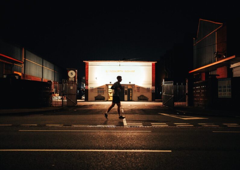 Fraser Morrison running past dark buildings in Manchester