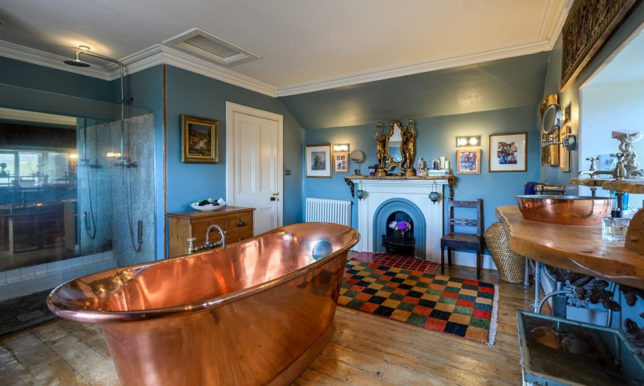 The bathroom has a copper bath and an original fireplace. 