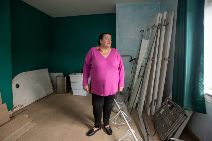 June Soutarin the middle of room with no carpet and doors and boxes leaning against the walls