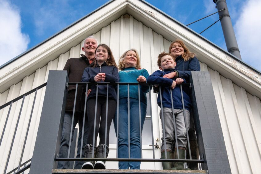 The family behind Fossoway stables stand on a balcony looking at the view over the estate.