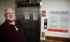 Eddie McHardy standing next to broken down lift at Dewar Court sheltered housing block in Perth