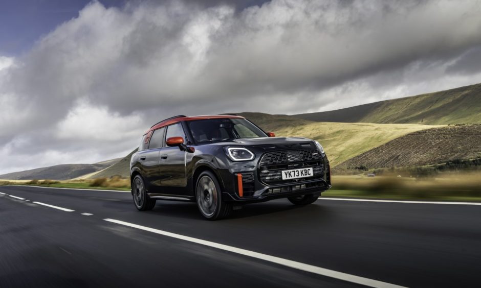 A black Mini Countryman on the road with hulls in the background