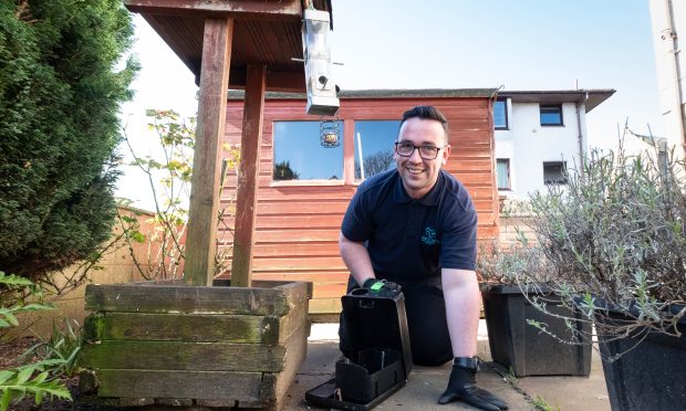 Alex Whelan puts measures in place to try and prevent rats from returning to a garden in Monifieth.
