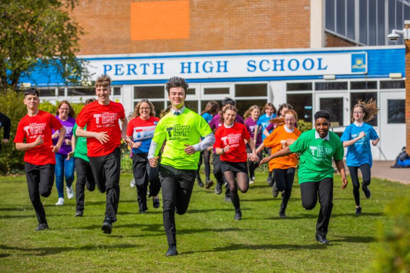 Perth High pupils running in colourful tops in front of the school