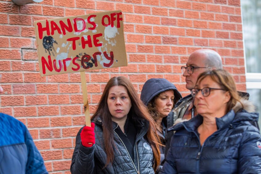Young woman holding a placard which reads 'hands off the nusery'