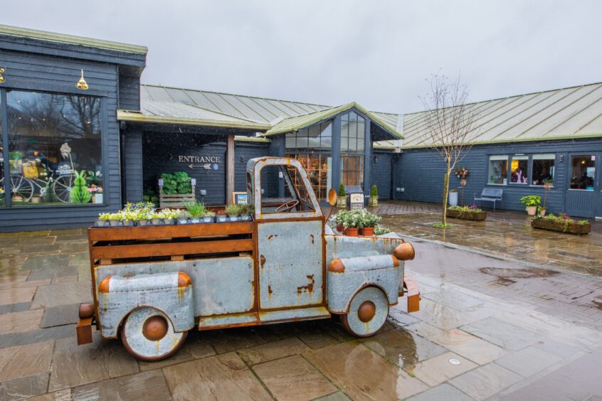 Loch Leven's Larder exterior with old fashioned vehicle now used as a stall for green plants in courtyard outside