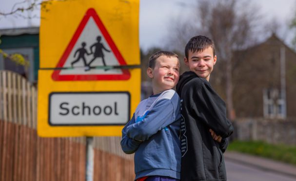 Ben and Charlie Lothian beside a school crossing sign.