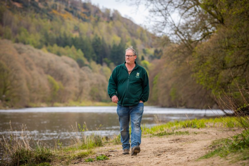 Victor Clements walking on path beside tree-lined river