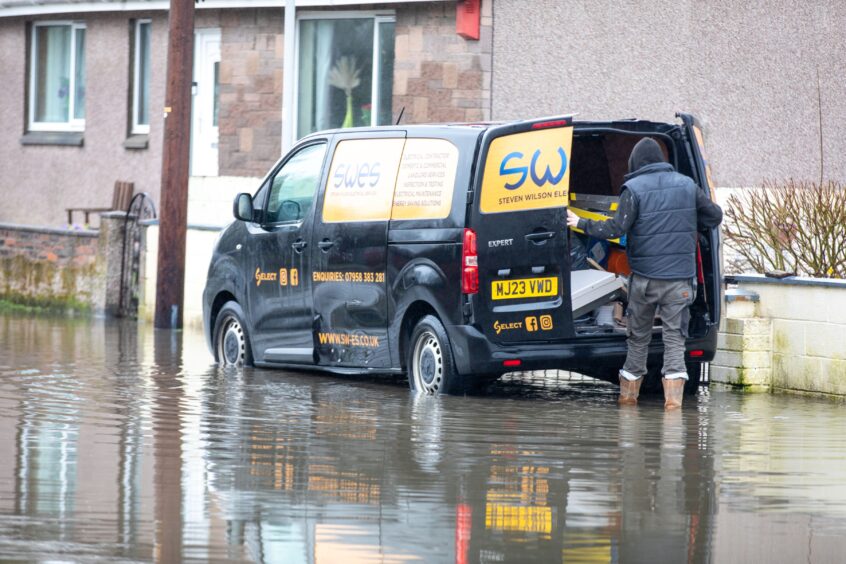 A builder at Park Road in Rosyth attempts to unload his van despite the flooding.