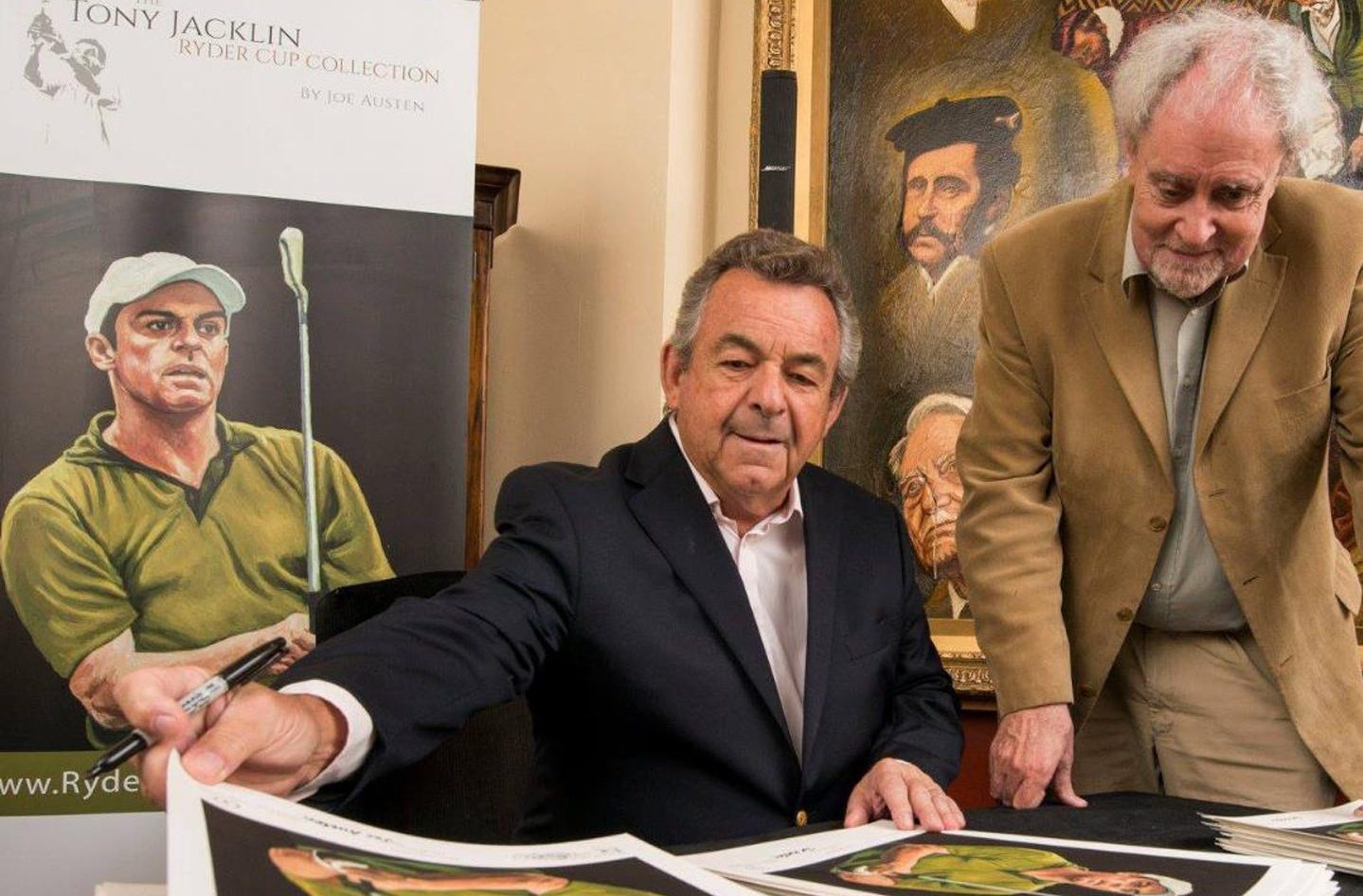 Tony Jacklin signing portraits at a table with Joe Austen leaning beside him