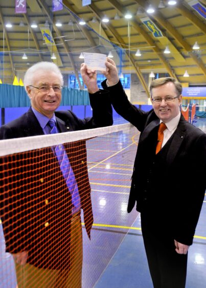 Ian Brown accepting cheque from councillor Alexander Stewart across a badminton net at the Bell's Sports Centre, Perth