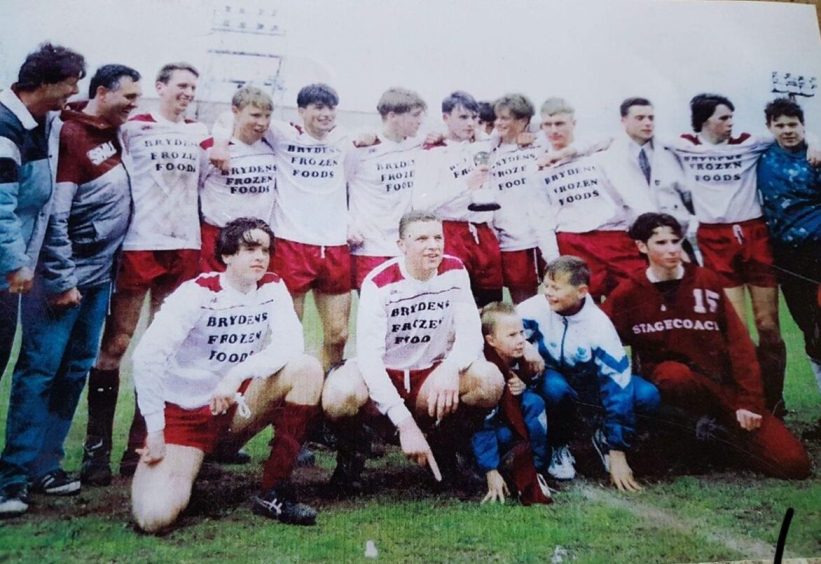 Line-up of junior footballers with manager Jimmy Carle smiling at back