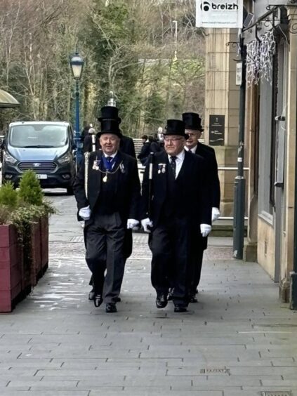 Sandy Scrimgeour walking on Perth Street with others in High Constables outfit of top hat and dress uniform