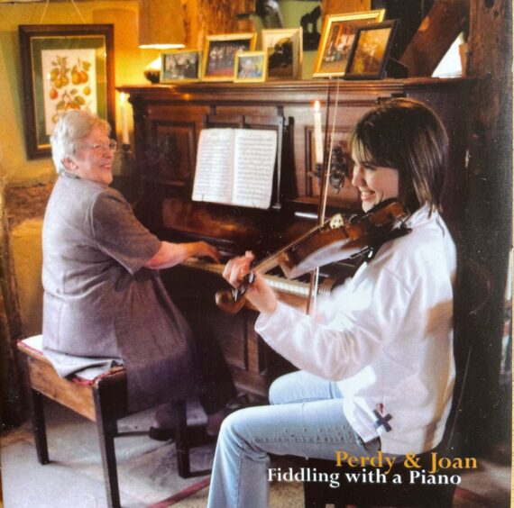 CD cover showing Joan Blue smiling on piano while Perdy Syers Gibson plays violin