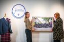 Hannah Cain of Strathmore Woollen Company and Rachel Jackson of Angus Alive hang a photo in the Piping Routes exhibition.