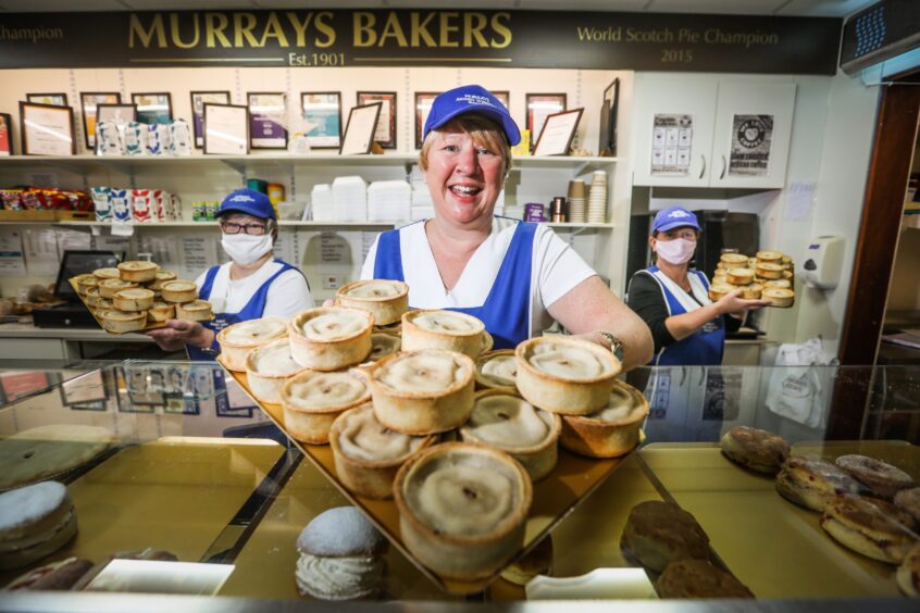Linda Hill inside Murray's bakers holding big tray of pies