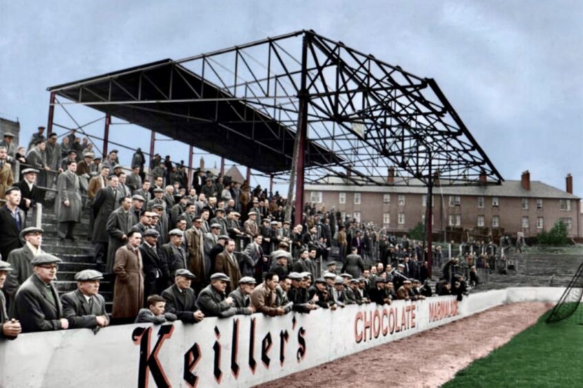 A colourised photo of The Shed during construction, with only the metal girders and one section of roofing in place at Tannadice Park