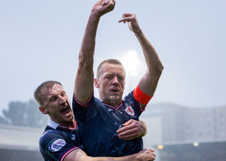 Scott Brown raises both arms in the air in celebration as Raith Rovers team-mate Liam Dick throws his arms around him.