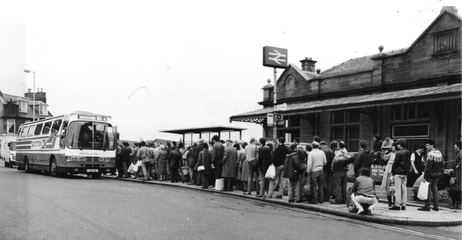 People queue to board a rail replacement bus.