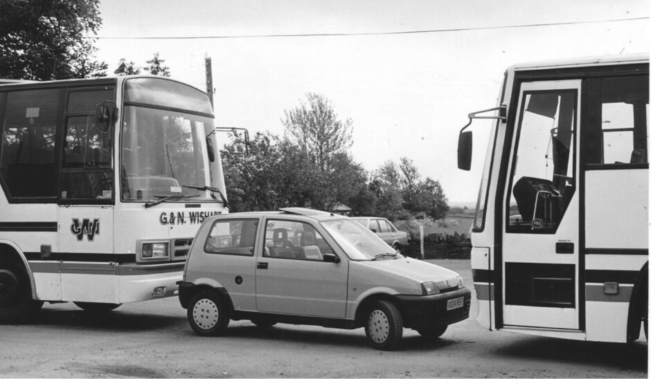 A Fiat gets parked in between two buses in 1993.